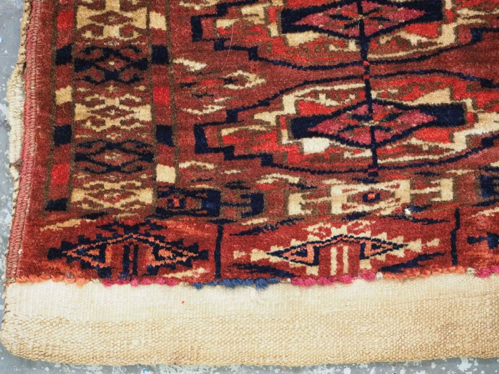 A small rectangular 19th-century Tekke Turkmen wool torba featuring nine geometric guls on a deep red field with an attached cream wool backing. View V