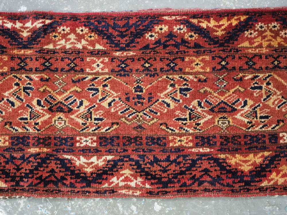 A long horizontal antique Ersari Turkmen wool woven bag face featuring intricate geometric tribal patterns in dark red, navy blue, yellow, and cream tones. View IV