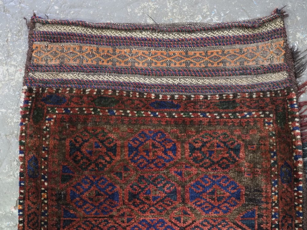 An antique woven Baluch Balisht storage bag featuring dark red and navy blue geometric octagonal motifs with a flat-weave top border and fringed edges. View II