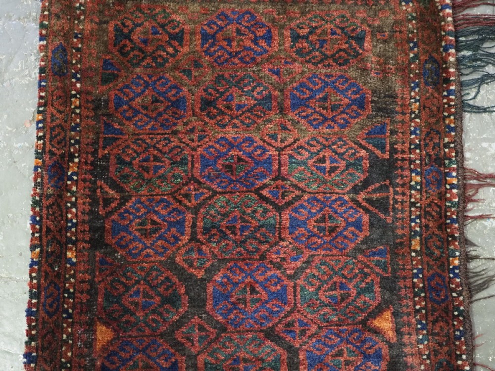 An antique woven Baluch Balisht storage bag featuring dark red and navy blue geometric octagonal motifs with a flat-weave top border and fringed edges. View III