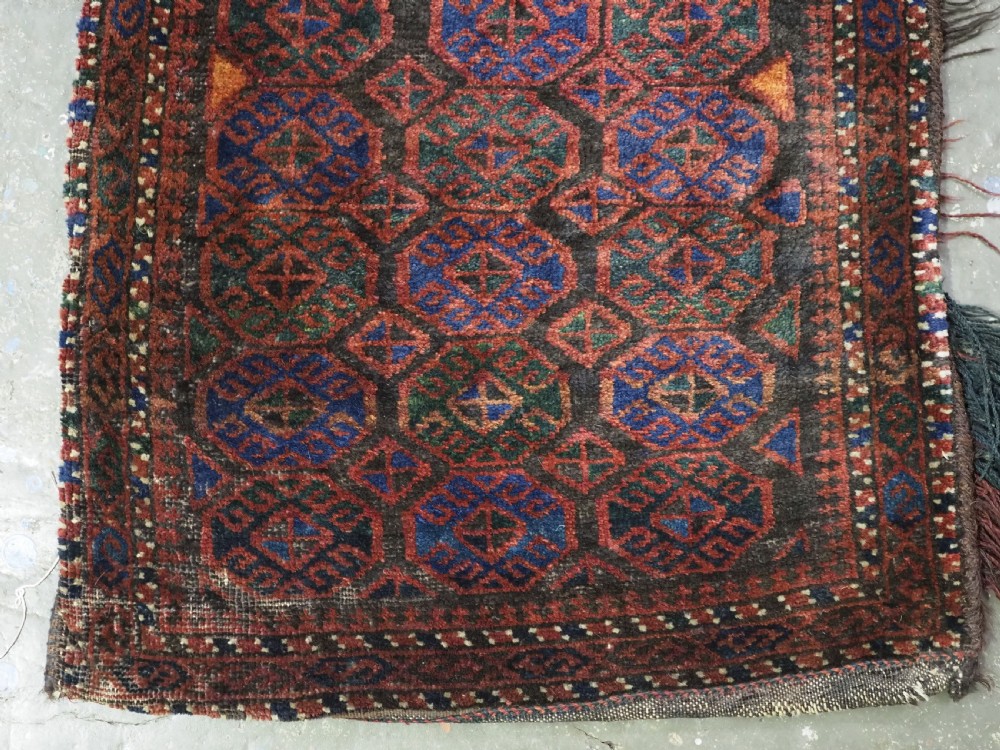 An antique woven Baluch Balisht storage bag featuring dark red and navy blue geometric octagonal motifs with a flat-weave top border and fringed edges. View IV