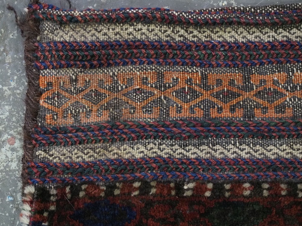 An antique woven Baluch Balisht storage bag featuring dark red and navy blue geometric octagonal motifs with a flat-weave top border and fringed edges. View V