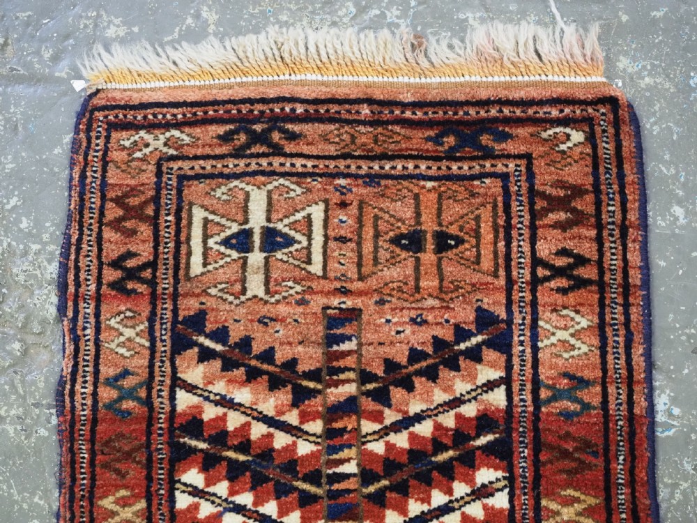 An antique hand-knotted Yomut Turkmen woven bag face featuring intricate geometric serrated motifs in terracotta, navy, and cream with fringed borders. View IV