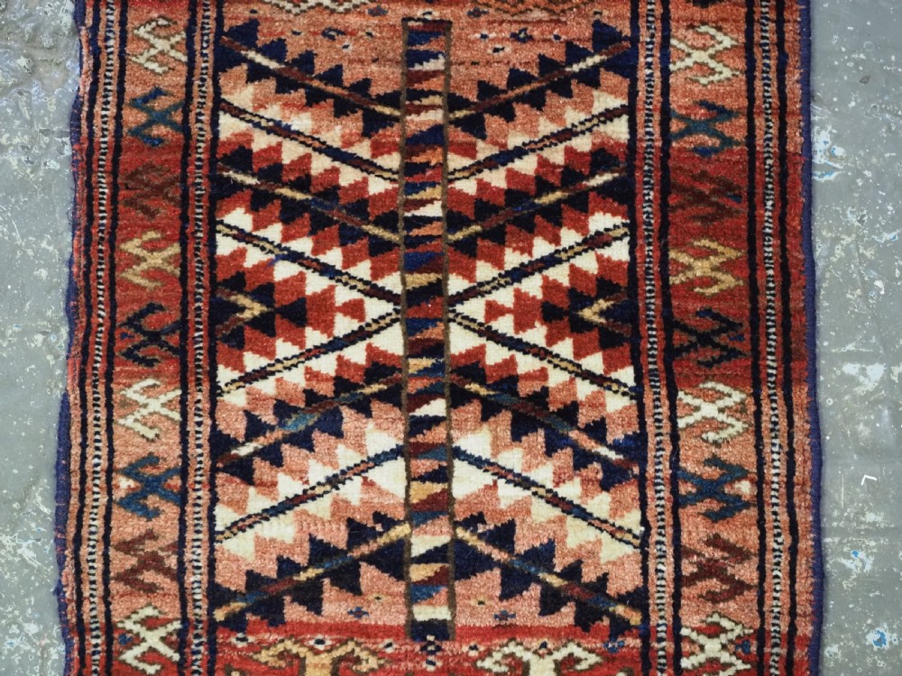 An antique hand-knotted Yomut Turkmen woven bag face featuring intricate geometric serrated motifs in terracotta, navy, and cream with fringed borders. View V