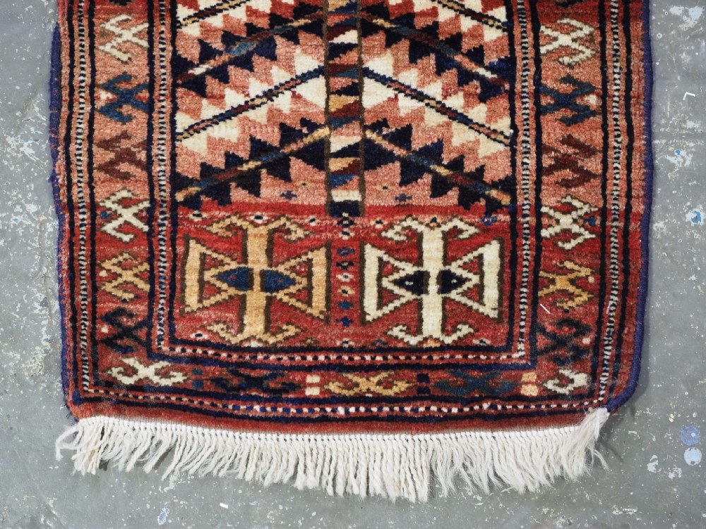 An antique hand-knotted Yomut Turkmen woven bag face featuring intricate geometric serrated motifs in terracotta, navy, and cream with fringed borders. View VI
