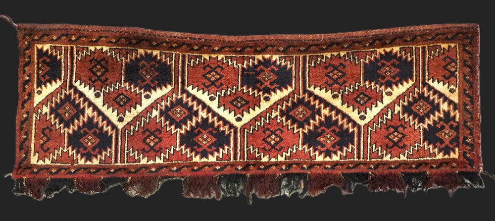 An antique rectangular Ersari Turkmen torba bag face featuring geometric curled leaf motifs in navy blue and terracotta red on an ivory background with fringed trim.