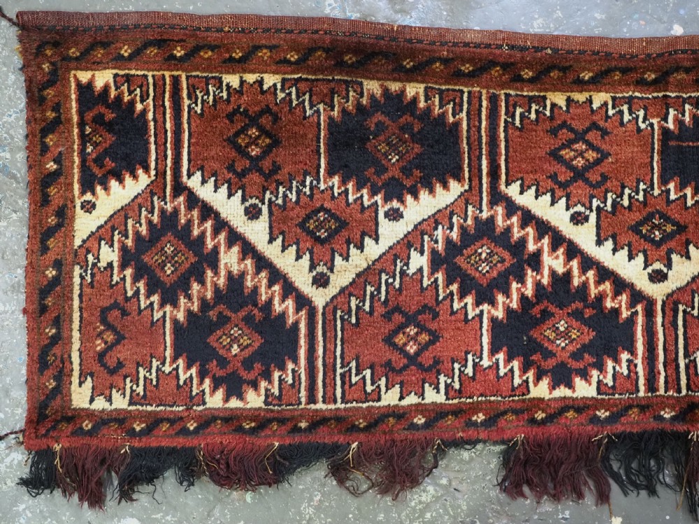 An antique rectangular Ersari Turkmen torba bag face featuring geometric curled leaf motifs in navy blue and terracotta red on an ivory background with fringed trim. View II