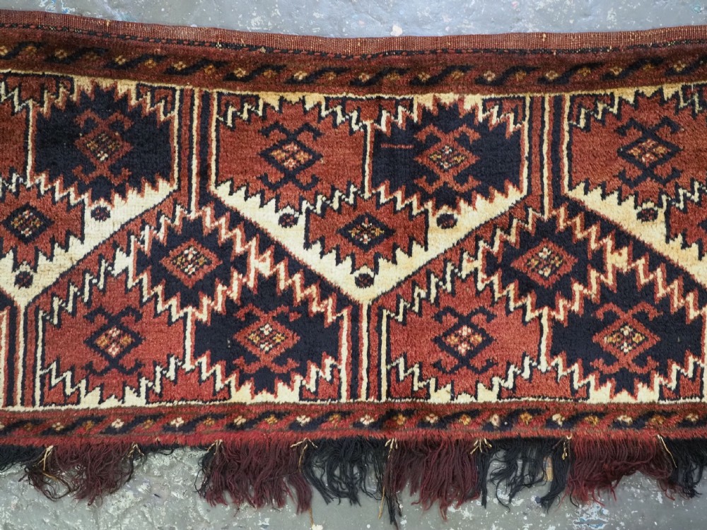 An antique rectangular Ersari Turkmen torba bag face featuring geometric curled leaf motifs in navy blue and terracotta red on an ivory background with fringed trim. View III