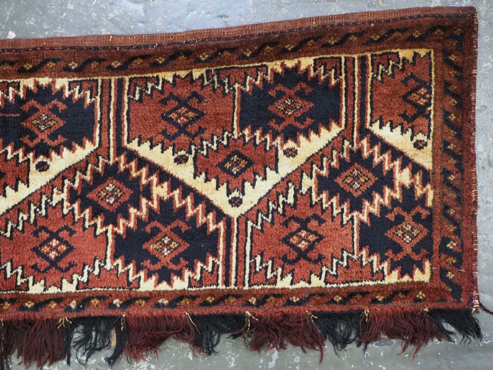 An antique rectangular Ersari Turkmen torba bag face featuring geometric curled leaf motifs in navy blue and terracotta red on an ivory background with fringed trim. View IV