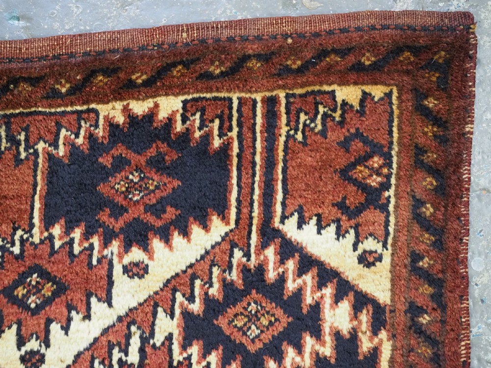 An antique rectangular Ersari Turkmen torba bag face featuring geometric curled leaf motifs in navy blue and terracotta red on an ivory background with fringed trim. View VI