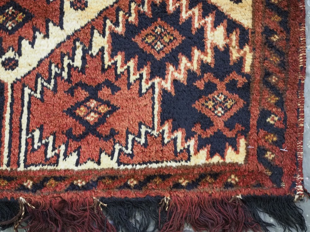 An antique rectangular Ersari Turkmen torba bag face featuring geometric curled leaf motifs in navy blue and terracotta red on an ivory background with fringed trim. View VIII