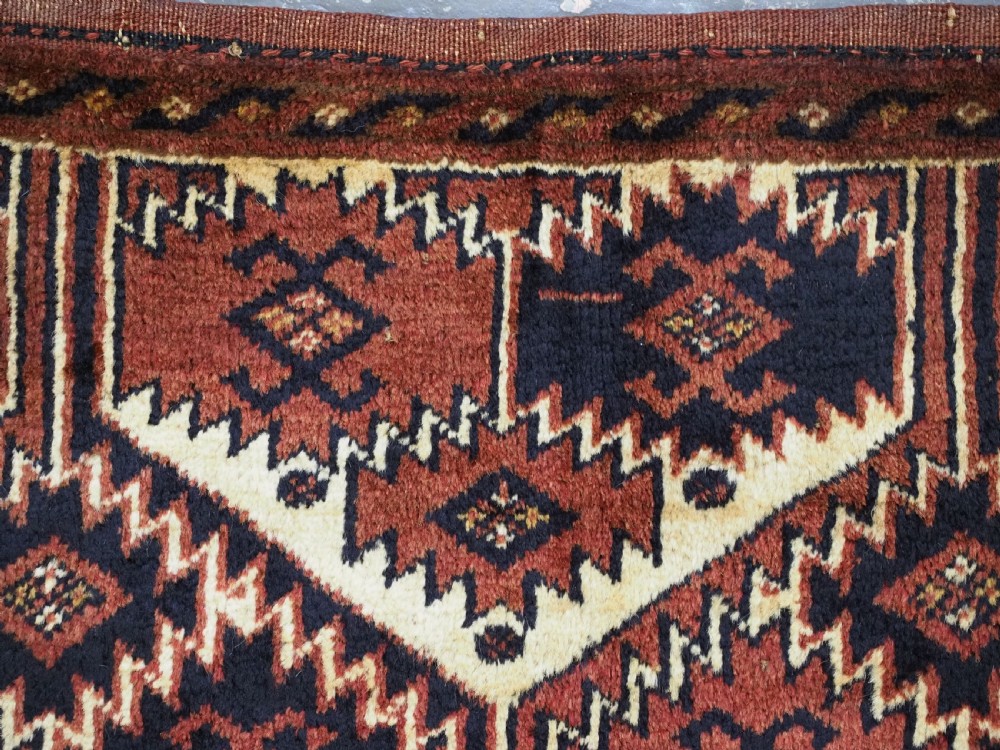 An antique rectangular Ersari Turkmen torba bag face featuring geometric curled leaf motifs in navy blue and terracotta red on an ivory background with fringed trim. View IX