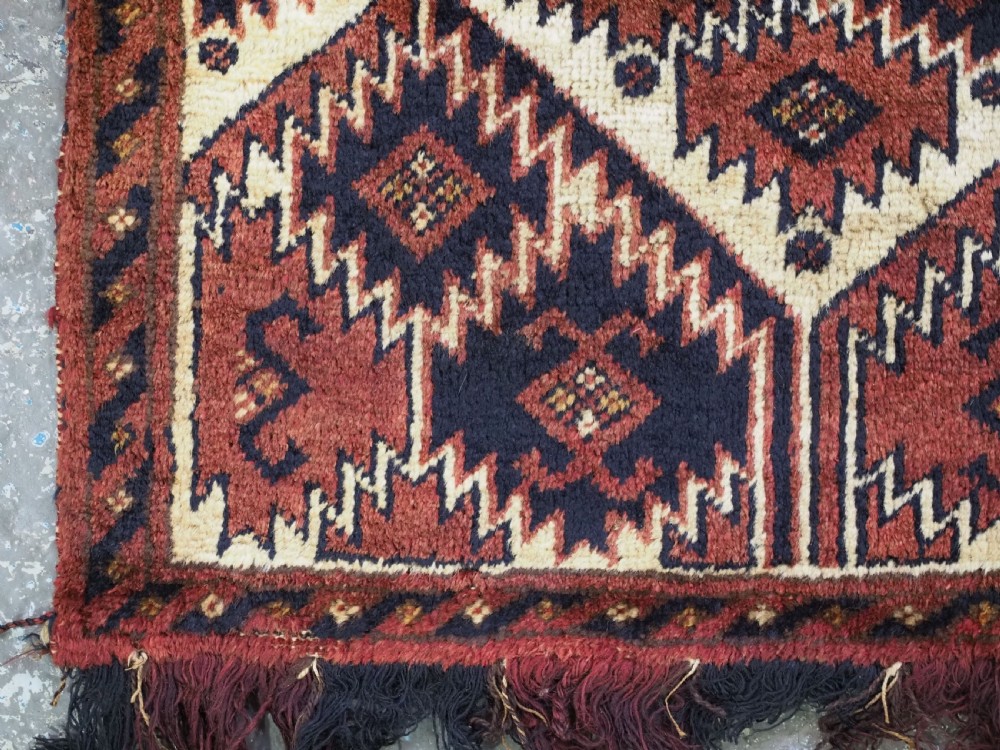 An antique rectangular Ersari Turkmen torba bag face featuring geometric curled leaf motifs in navy blue and terracotta red on an ivory background with fringed trim. View XI