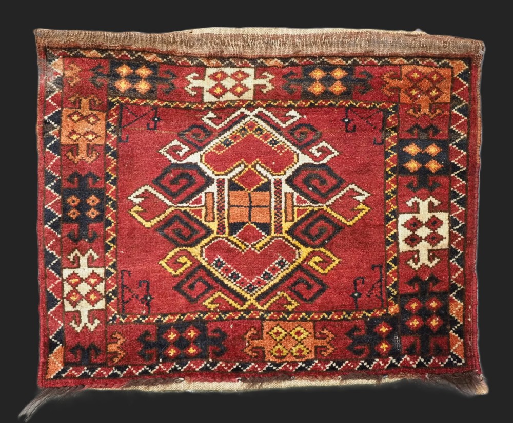 A hand-knotted wool Ersari Turkmen storage bag face featuring a central geometric medallion framed by intricate decorative borders in red, navy blue, yellow, and cream.