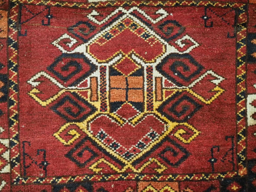 A hand-knotted wool Ersari Turkmen storage bag face featuring a central geometric medallion framed by intricate decorative borders in red, navy blue, yellow, and cream. View V