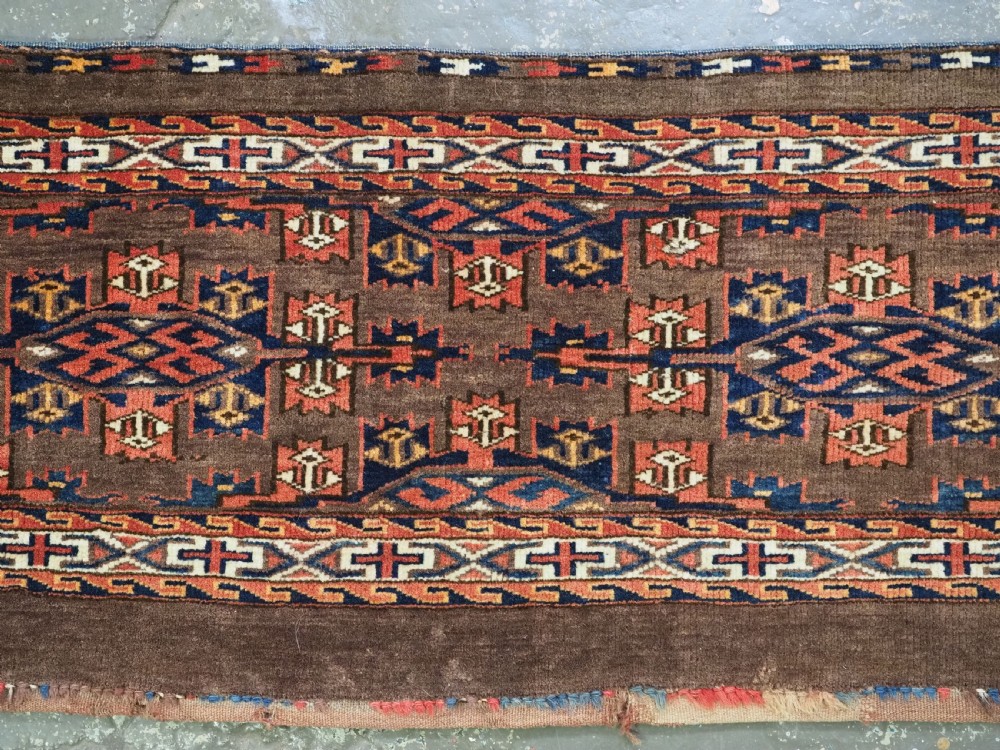 A horizontal rectangular handwoven wool Turkmen torba bag featuring geometric Kepse gul motifs in red and navy on a dark brown ground. View III