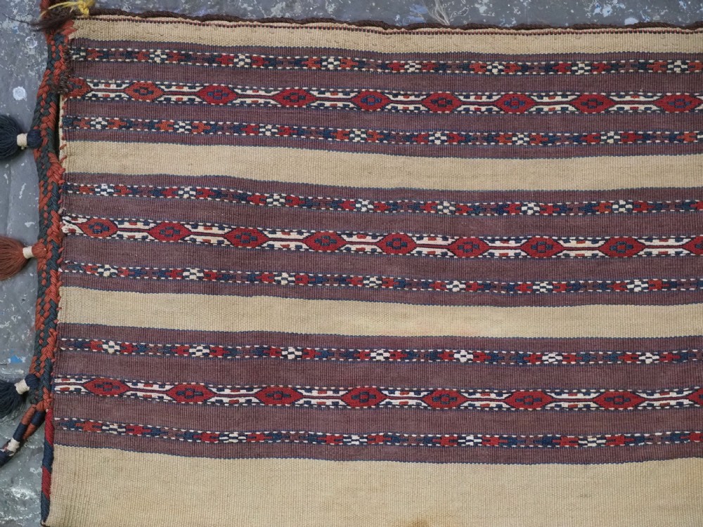 An antique Turkmen flatweave panel with horizontal cream, dark brown, and terracotta geometric bands decorated with side tassels and fringing. View II