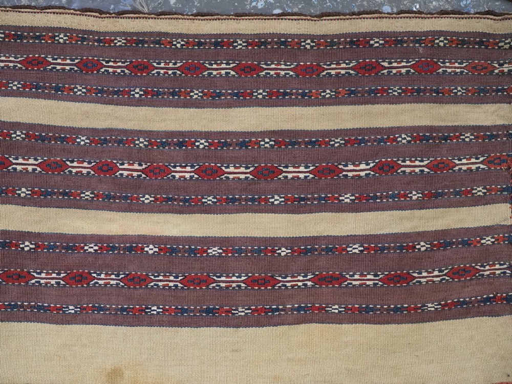 An antique Turkmen flatweave panel with horizontal cream, dark brown, and terracotta geometric bands decorated with side tassels and fringing. View IV