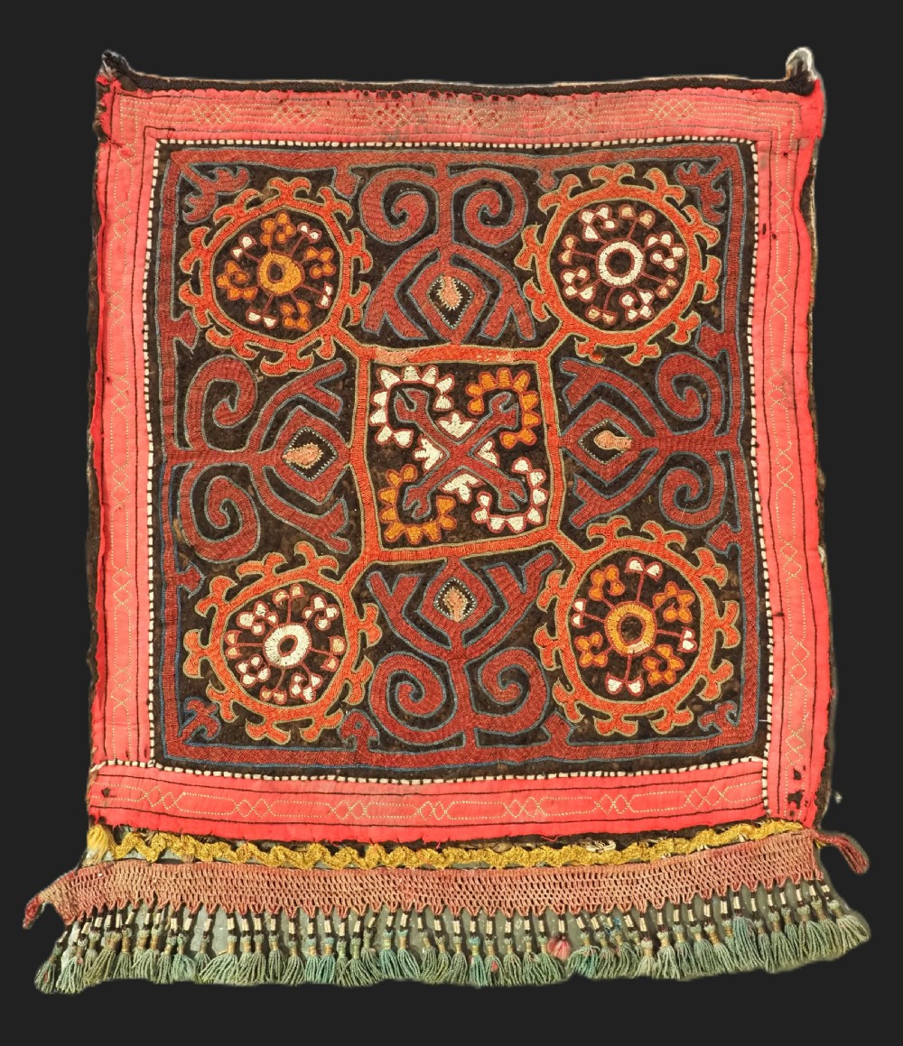 An antique square Kirghiz felt panel featuring central scroll embroidery in red, yellow, and white, framed by a red border with applied tasselled fringe at the bottom edge.