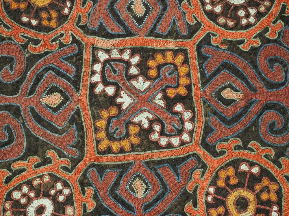 An antique square Kirghiz felt panel featuring central scroll embroidery in red, yellow, and white, framed by a red border with applied tasselled fringe at the bottom edge. View III