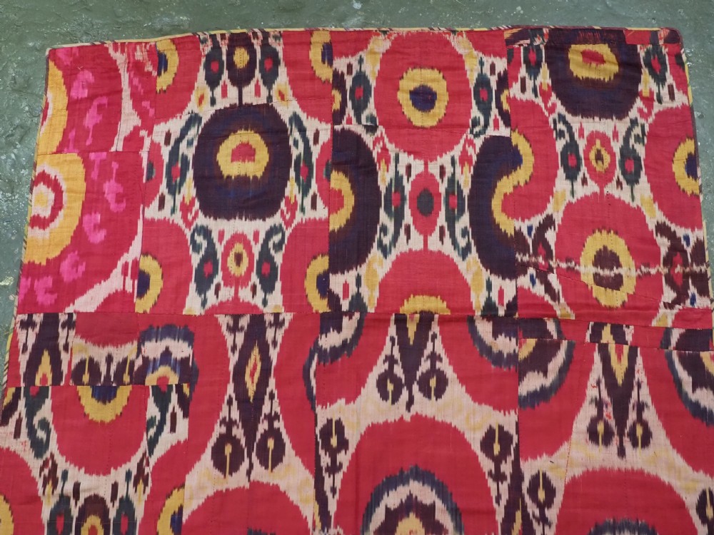 A vertical handwoven silk ikat textile panel featuring bold crimson, yellow, and deep purple circular geometric patterns on an off-white background. View III