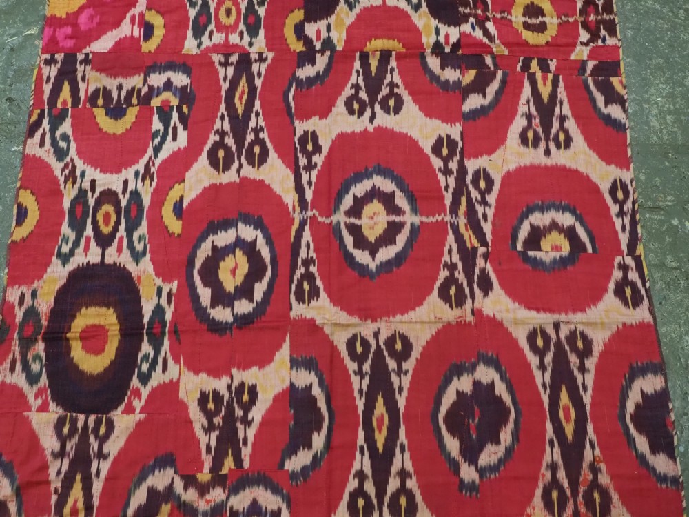 A vertical handwoven silk ikat textile panel featuring bold crimson, yellow, and deep purple circular geometric patterns on an off-white background. View IV