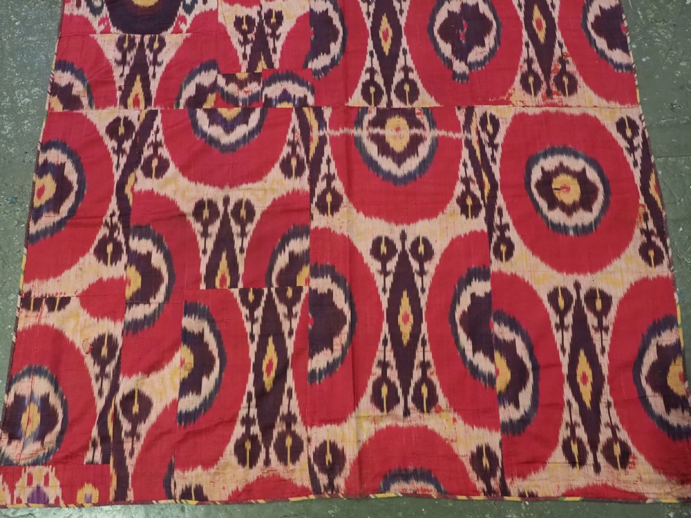 A vertical handwoven silk ikat textile panel featuring bold crimson, yellow, and deep purple circular geometric patterns on an off-white background. View VI