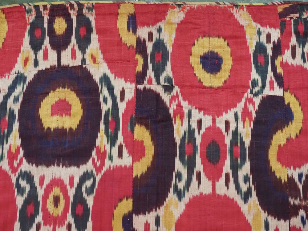 A vertical handwoven silk ikat textile panel featuring bold crimson, yellow, and deep purple circular geometric patterns on an off-white background. View VII