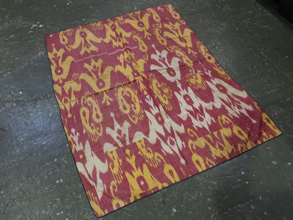 An antique Uzbek silk adras ikat panel featuring bold floral and geometric motifs in crimson red, mustard yellow, and cream. View II