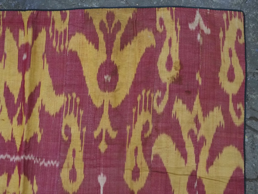 An antique Uzbek silk adras ikat panel featuring bold floral and geometric motifs in crimson red, mustard yellow, and cream. View VI
