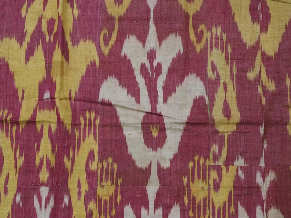 An antique Uzbek silk adras ikat panel featuring bold floral and geometric motifs in crimson red, mustard yellow, and cream. View VII