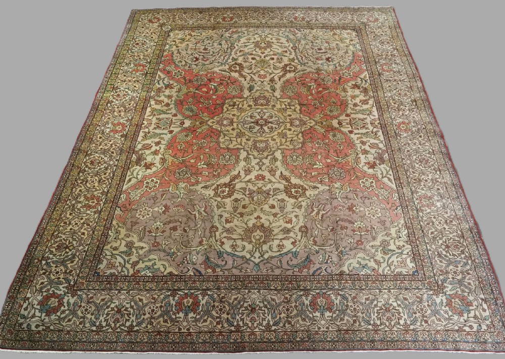 An antique hand-knotted Tabriz carpet featuring a central floral medallion, ornate spandrels, and a multi-tiered border in terracotta, cream, and soft pastel shades.