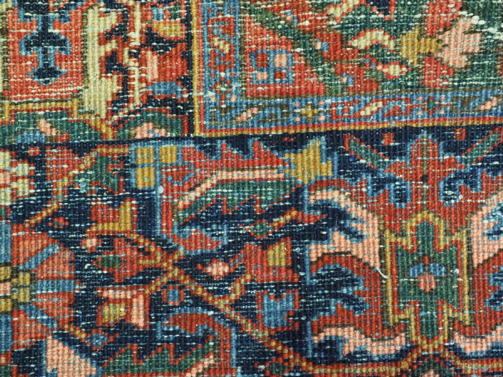 An antique hand-knotted Persian Heriz wool carpet featuring a central geometric medallion, angular spandrels, a terracotta red field, and navy blue borders. View XIII