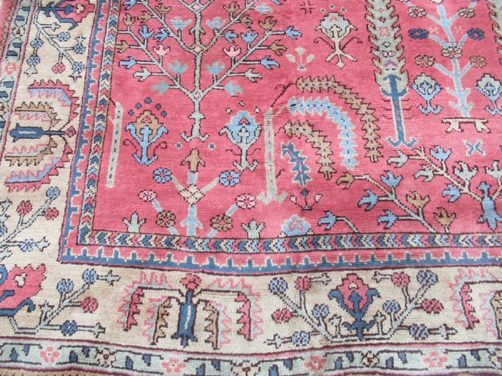 An antique Turkish Oushak wool carpet featuring a dominant pink ground decorated with stylized willow tree motifs and framed by a light beige floral border. View II