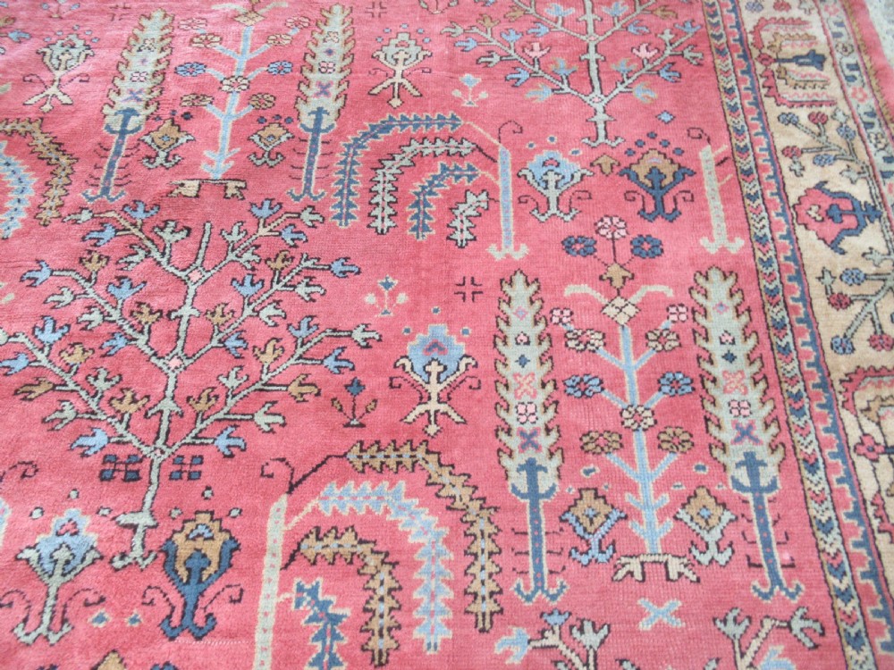 An antique Turkish Oushak wool carpet featuring a dominant pink ground decorated with stylized willow tree motifs and framed by a light beige floral border. View III