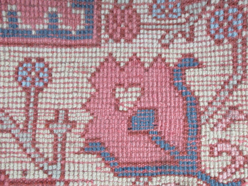 An antique Turkish Oushak wool carpet featuring a dominant pink ground decorated with stylized willow tree motifs and framed by a light beige floral border. View IV
