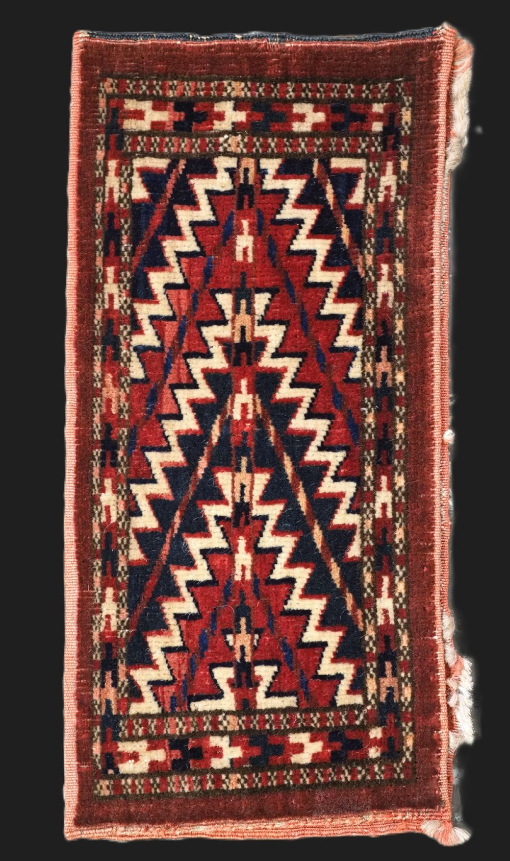 An antique handwoven Yomut Turkmen spindle bag face with geometric red, navy, and ivory serrated zigzag patterns. View II