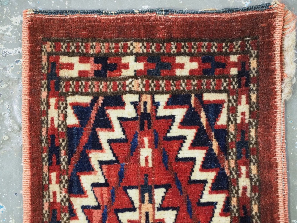 An antique handwoven Yomut Turkmen spindle bag face with geometric red, navy, and ivory serrated zigzag patterns. View III