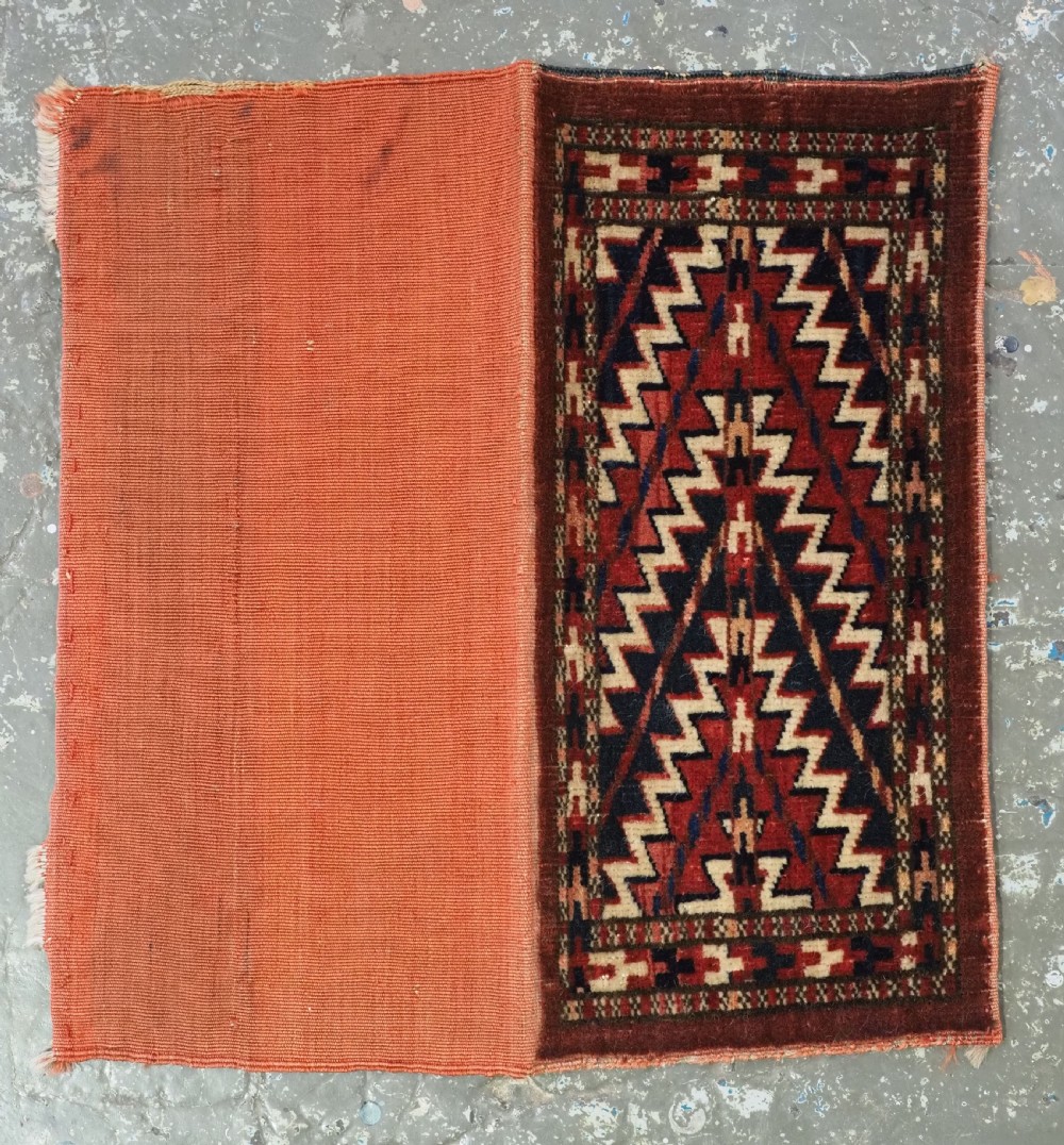 An antique handwoven Yomut Turkmen spindle bag face with geometric red, navy, and ivory serrated zigzag patterns. View VII