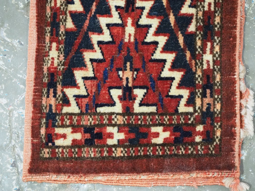 An antique handwoven Yomut Turkmen spindle bag face with geometric red, navy, and ivory serrated zigzag patterns. View VIII