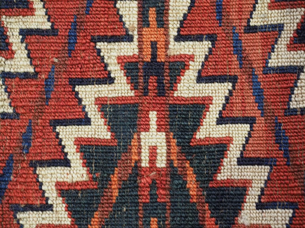 An antique handwoven Yomut Turkmen spindle bag face with geometric red, navy, and ivory serrated zigzag patterns. View IX
