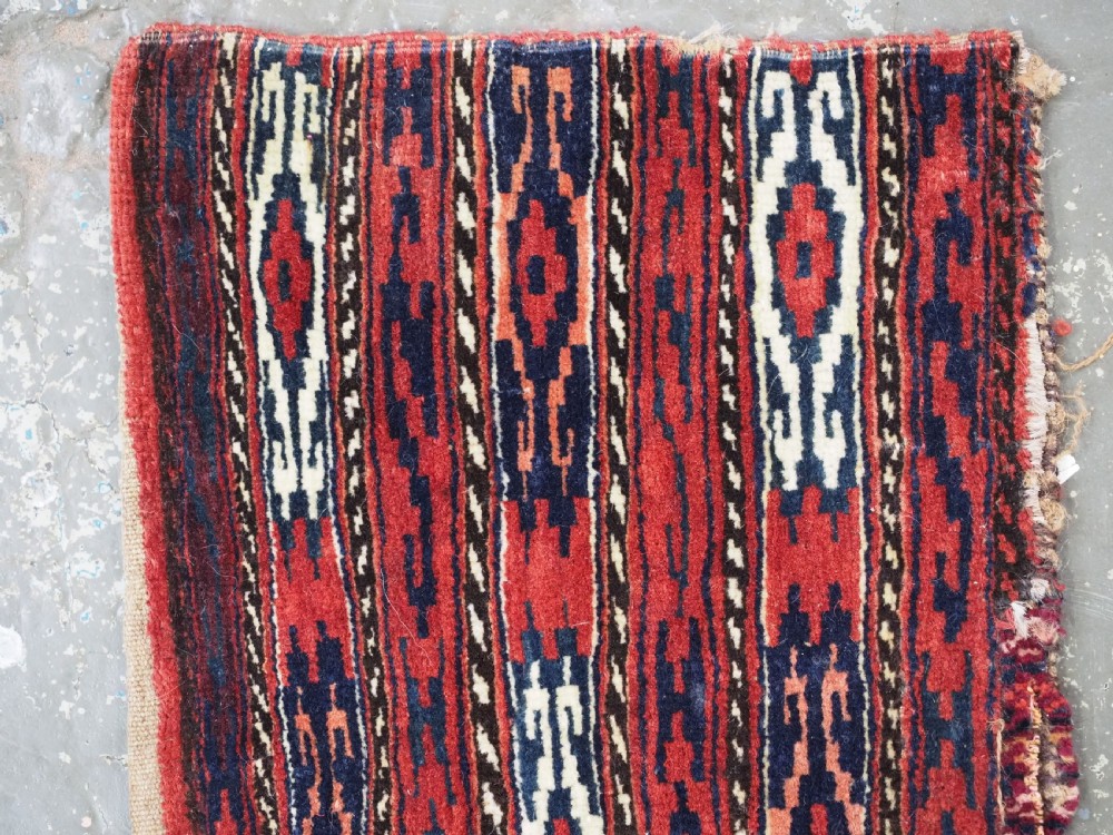 A vertical hand-woven wool Turkmen spindle bag featuring vertical geometric striped patterns in deep red, navy blue, and ivory tones. View II