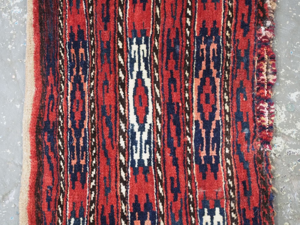 A vertical hand-woven wool Turkmen spindle bag featuring vertical geometric striped patterns in deep red, navy blue, and ivory tones. View III