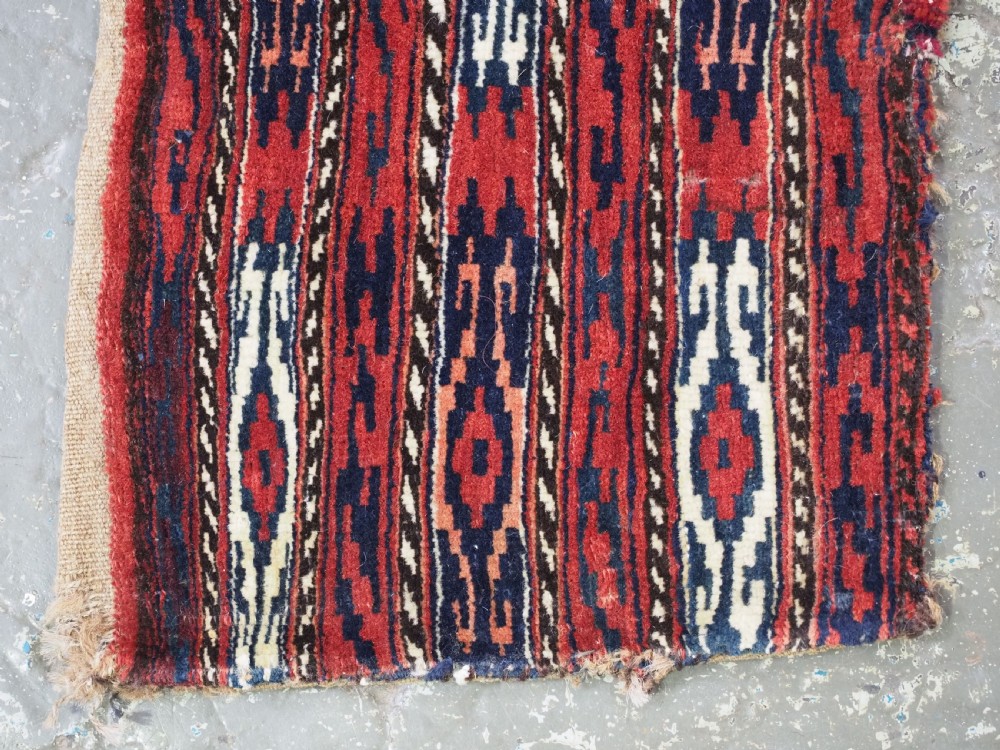 A vertical hand-woven wool Turkmen spindle bag featuring vertical geometric striped patterns in deep red, navy blue, and ivory tones. View IV