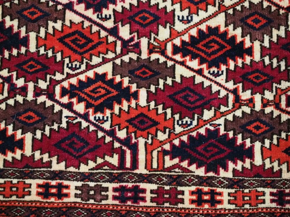 An antique rectangular Tekke Turkmen woven torba face featuring a geometric diamond lattice pattern in burgundy, cream, and orange, finished with long polychrome wool fringes along the lower edge. View VIII