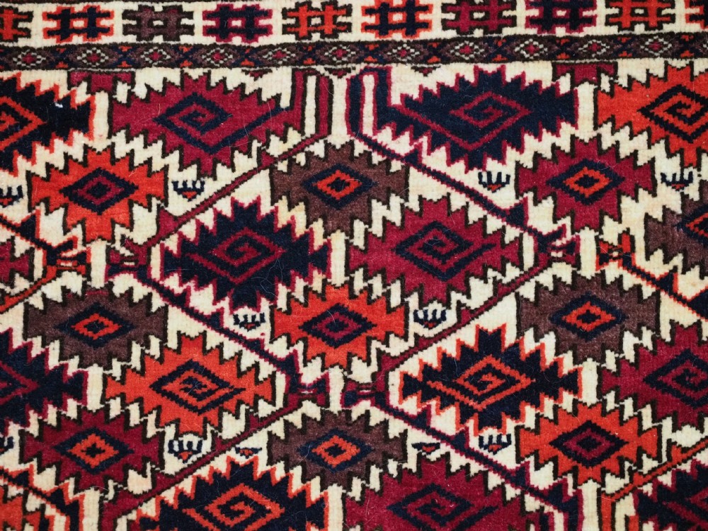An antique rectangular Tekke Turkmen woven torba face featuring a geometric diamond lattice pattern in burgundy, cream, and orange, finished with long polychrome wool fringes along the lower edge. View IX