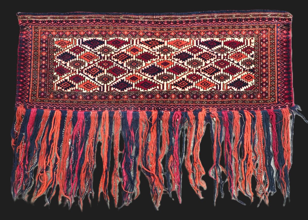 An antique Tekke Turkmen torba face featuring a geometric curled leaf diamond pattern on an ivory field with a thick wool fringe.