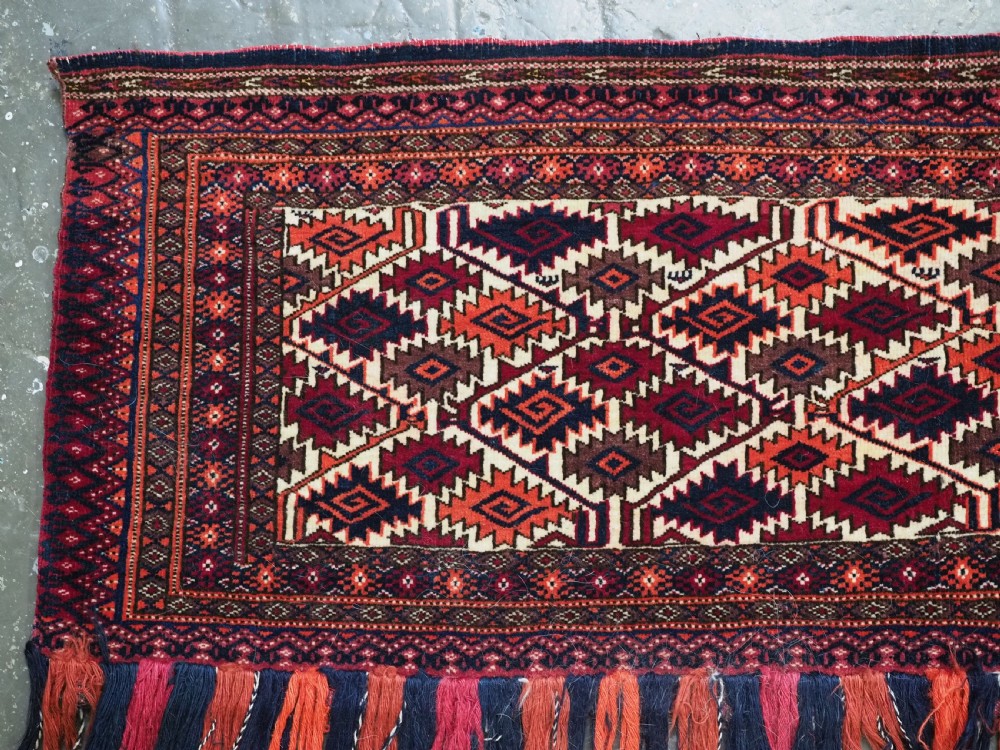 An antique Tekke Turkmen torba face featuring a geometric curled leaf diamond pattern on an ivory field with a thick wool fringe. View III