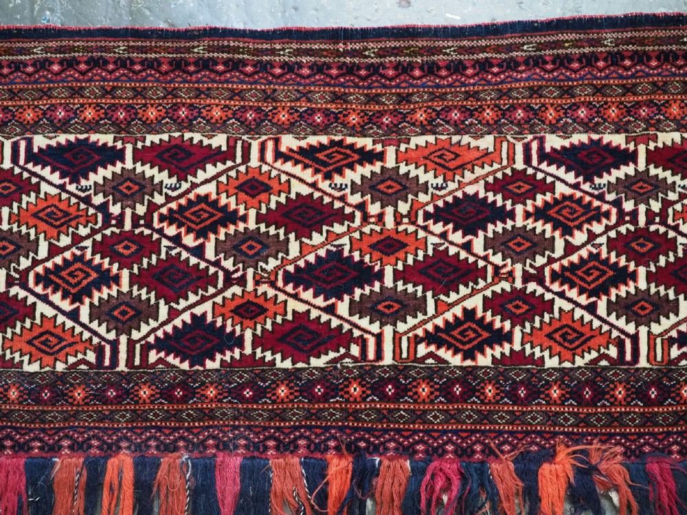 An antique Tekke Turkmen torba face featuring a geometric curled leaf diamond pattern on an ivory field with a thick wool fringe. View IV