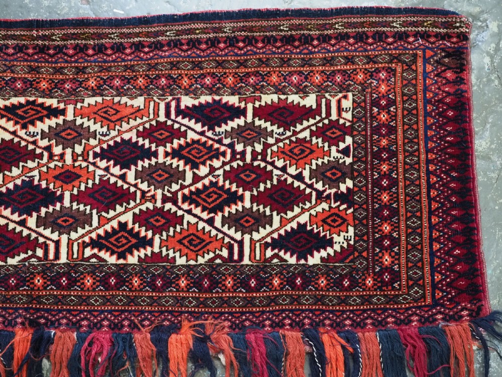 An antique Tekke Turkmen torba face featuring a geometric curled leaf diamond pattern on an ivory field with a thick wool fringe. View V